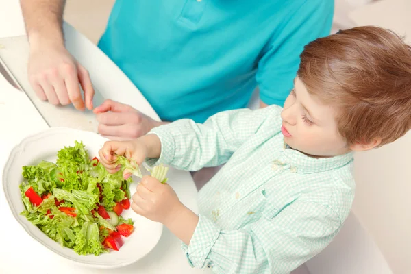 Pai e filho cozinham salada — Fotografia de Stock