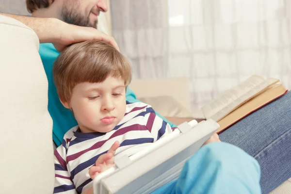 Padre e hijo leen un libro o tableta —  Fotos de Stock