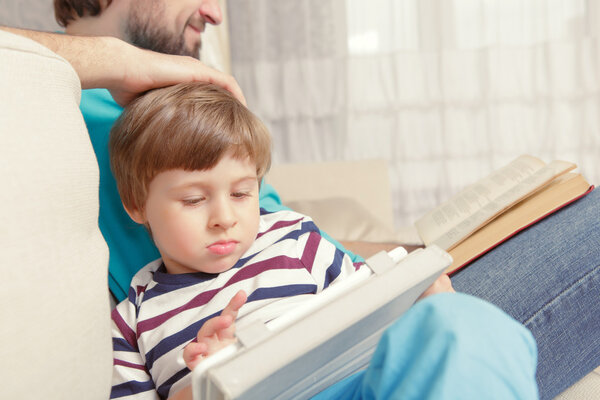 Father and son read a book or tablet