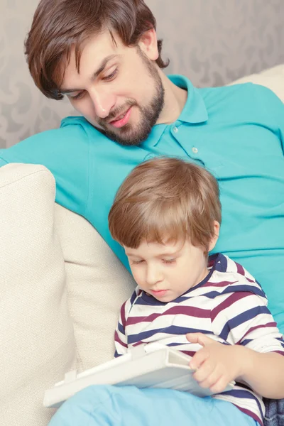 Padre e figlio leggono un libro o un tablet — Foto Stock