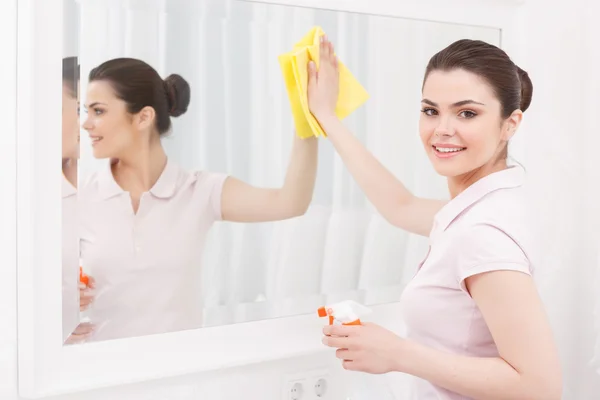Beautiful lady cleaning mirror — Stock Photo, Image