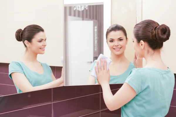 Beautiful lady cleaning mirror — Stock Photo, Image
