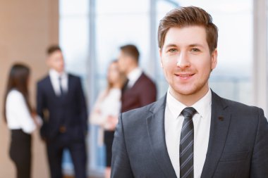 Young business man standing in front of his co-workers  talking clipart