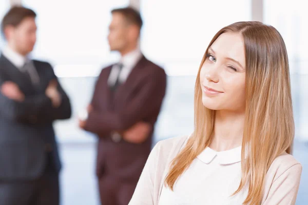 Blond young business woman standing in front of two men talking — Stock Photo, Image
