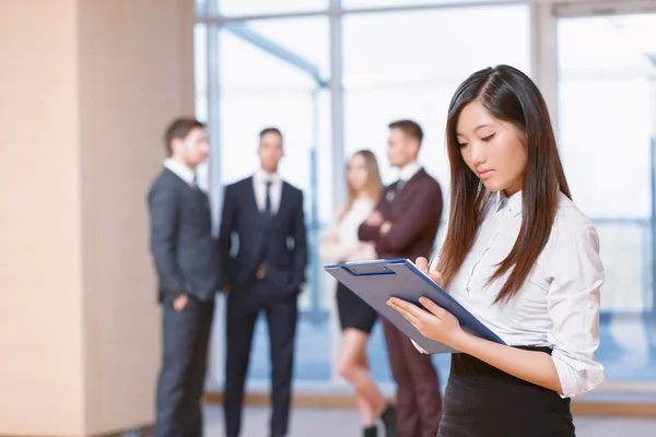 Asiática joven mujer de negocios de pie delante de sus compañeros de trabajo —  Fotos de Stock