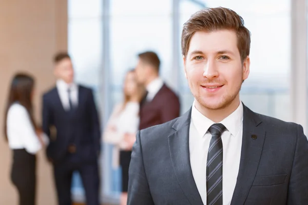 Joven hombre de negocios de pie frente a sus compañeros de trabajo hablando — Foto de Stock