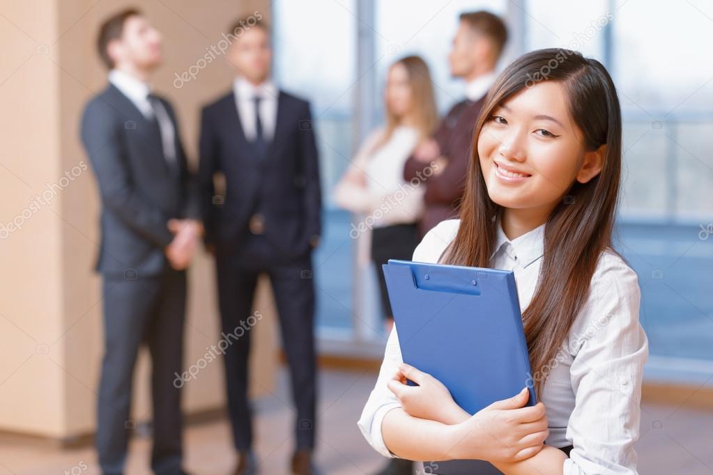 Asian young business woman standing in front of her co-workers