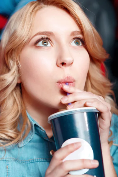 Молодая женщина с энтузиазмом пьет кокс в кино — стоковое фото
