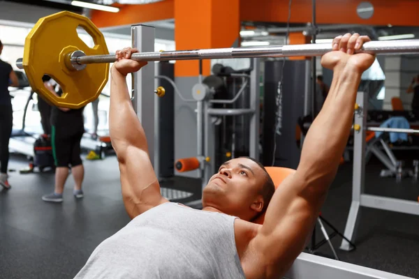 Sdraiato uomo sollevamento bilanciere in palestra — Foto Stock