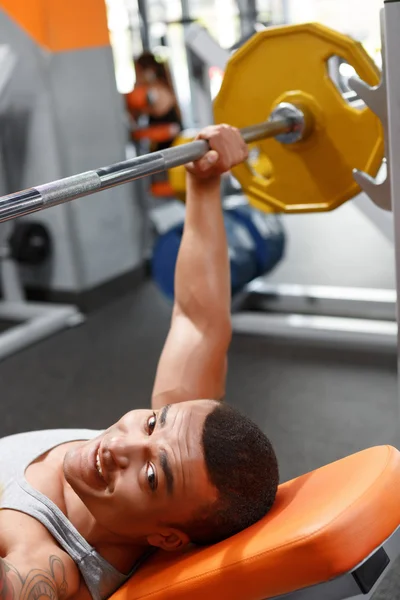 Sdraiato uomo sollevamento bilanciere in palestra — Foto Stock