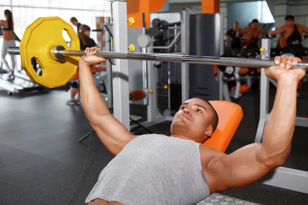 Hombre acostado levantando pesas en el gimnasio — Foto de Stock