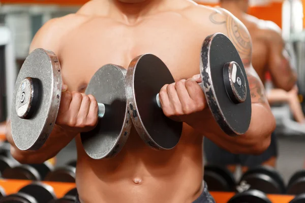 Man lyfta två hantlar i gym. — Stockfoto