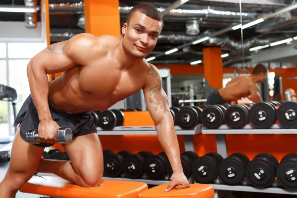 Homem muscular fazendo exercícios com halteres no ginásio — Fotografia de Stock