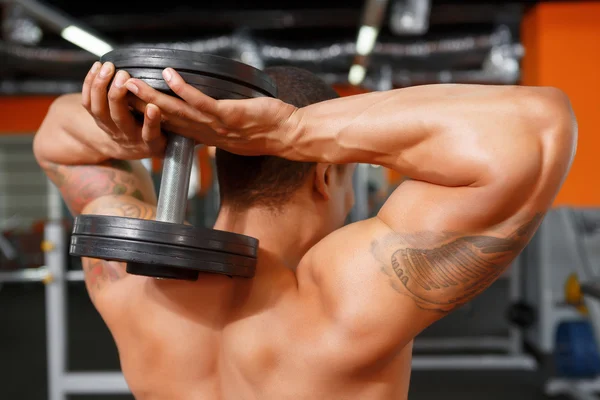 Hombre sosteniendo pesas detrás de su cabeza — Foto de Stock