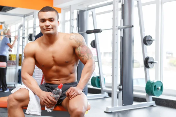 Man sitting with bottle and towel in gym — Stock Photo, Image