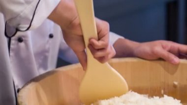Büyük ahşap kase pirinç karıştırma gülümseyen Asya şef in izleme çekim