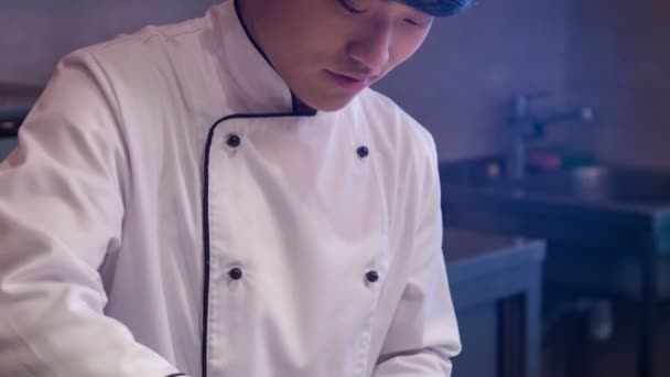 Tracking shot van lachende Aziatische chef-kok in wit uniform — Stockvideo