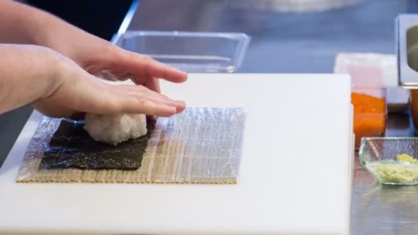 Ασιάτης/ισσα σεφ με λευκό στολή προετοιμασία ρολό σούσι — Αρχείο Βίντεο