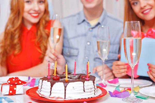 Jovens comemorando um aniversário sentados à mesa — Fotografia de Stock