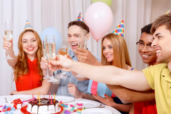 Jóvenes celebrando un cumpleaños sentados a la mesa —  Fotos de Stock