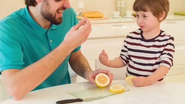 Sohn und Vater essen gemeinsam Zitrone — Stockvideo
