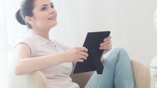 Mujer joven sentada mirando la foto — Vídeos de Stock