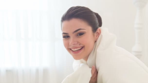 Joven mujer sonriente sentada en la cama — Vídeos de Stock