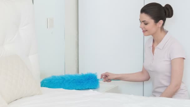 Молодая женщина вытирает пыль в спальне — стоковое видео
