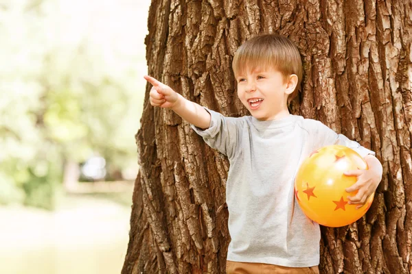 Jongen onder de boom met rubber bal naar boven gericht — Stockfoto