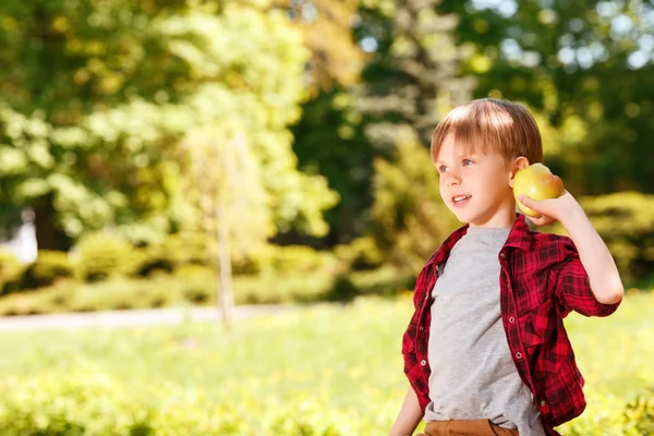 Boy going to throw apple in park. — Stock Photo, Image