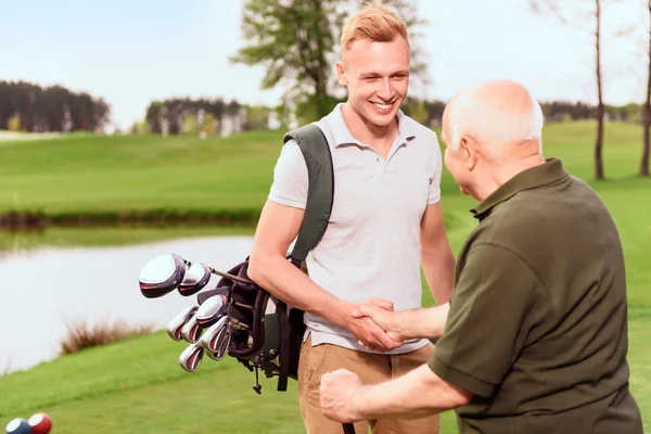 Jeunes et vieux joueurs de golf serrant la main — Photo