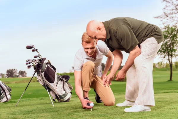 Dos hombres poniendo pelota en el tee en curso —  Fotos de Stock