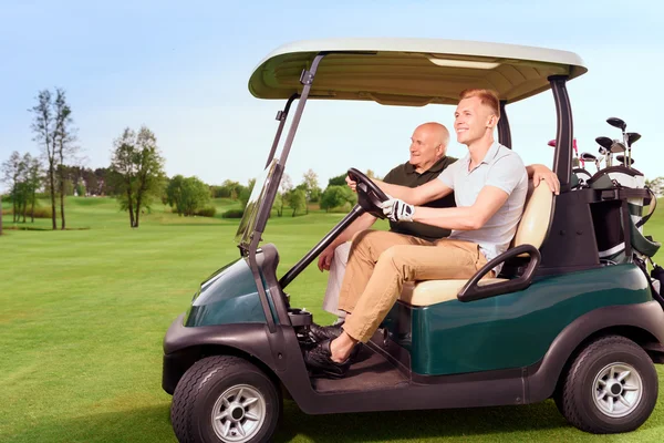 Vista lateral de dos golfistas carro de conducción —  Fotos de Stock