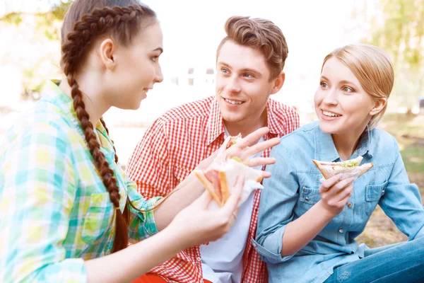Ungdomar sitter på omslaget och hålla smörgåsar — Stockfoto