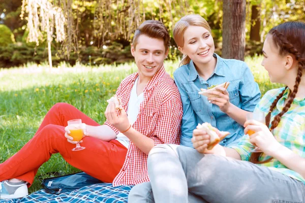 Unga människor äta och dricka under picknick — Stockfoto