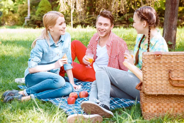 Unga människor äta och dricka under picknick — Stockfoto