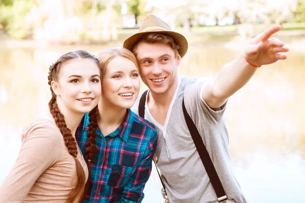 Hombre guapo con dos chicas señalando a un lado — Foto de Stock