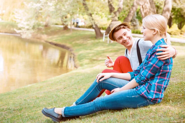 Junges Paar sitzt auf Gras am See — Stockfoto