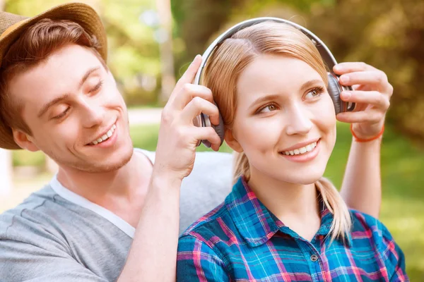 Bonito homem colocando fones de ouvido em menina bonita — Fotografia de Stock