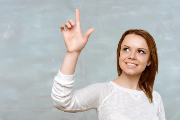 Young woman pointing upwards with her index finger. — Stock Photo, Image