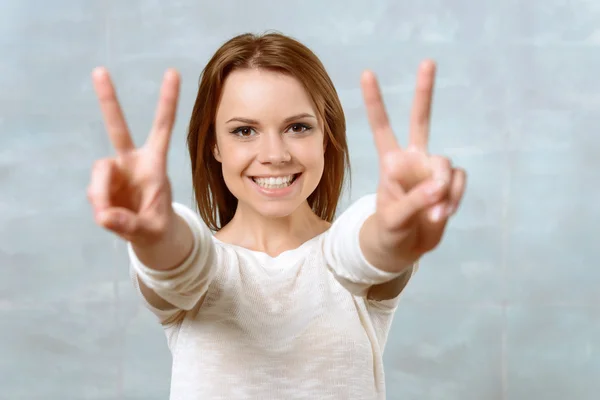 Smiling young woman showing two fingers — Stock Photo, Image