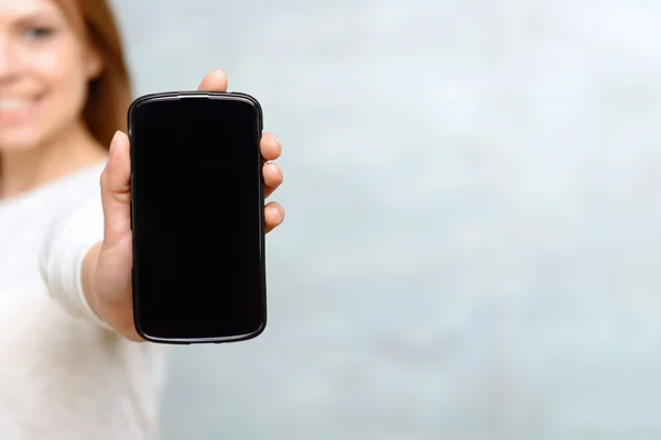 Lachende vrouw toont hij mobiele telefoon — Stockfoto