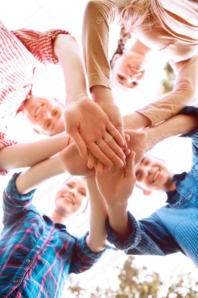 Young people in circle put their hands one of another 