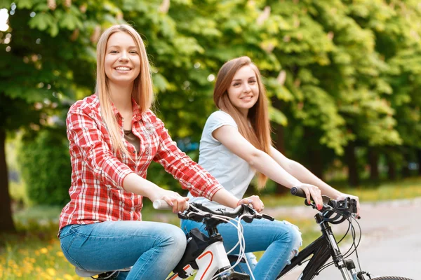 Chicas bonitas posando con bicicletas en el parque — Foto de Stock