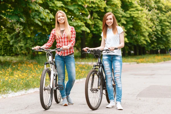 Chicas bonitas posando con bicicletas en el parque — Foto de Stock