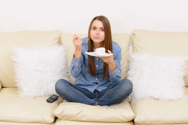 Fille regarder la télévision et manger sur le canapé . — Photo