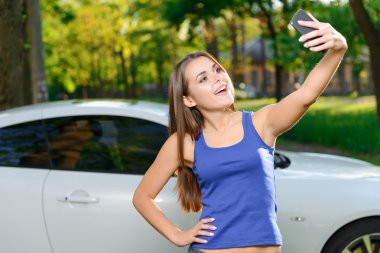 Gülümseyen kız selfie araba arka plan üzerinde yapıyor