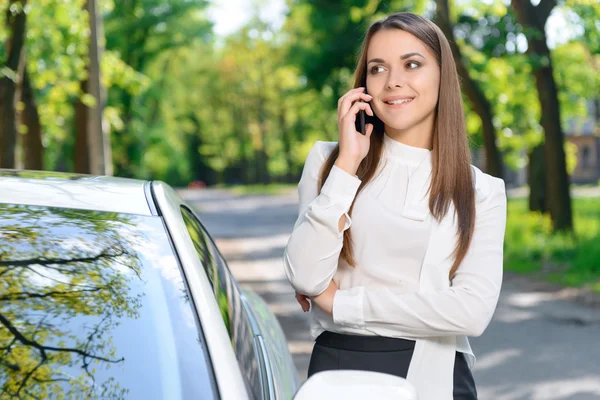 Žena hovoří za mobilní telefon u auta — Stock fotografie