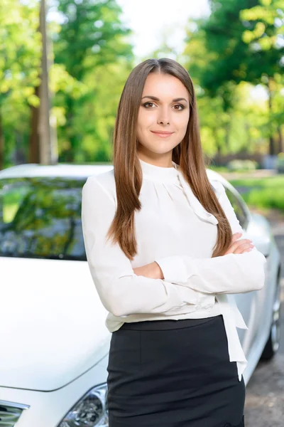 Молодая женщина стоит со скрещенными руками возле машины — стоковое фото