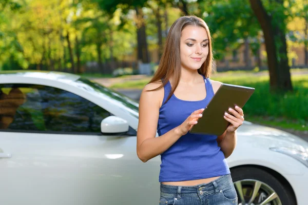 Linda dama de pie con la tableta cerca del coche — Foto de Stock